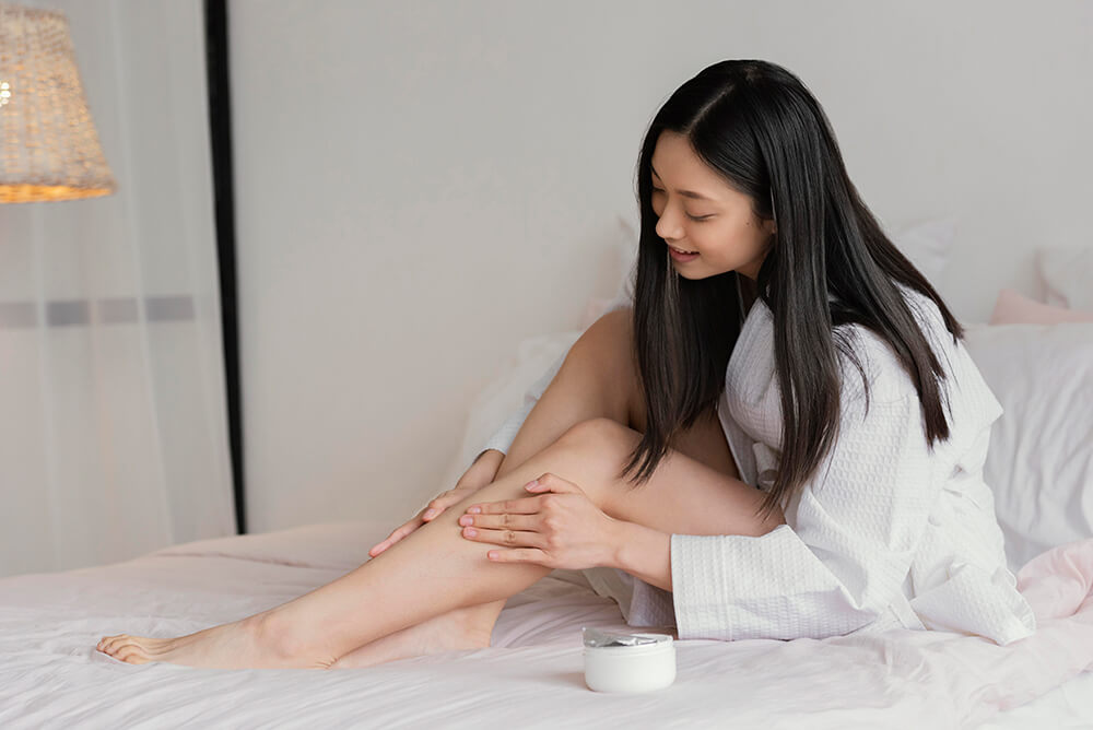 women applying moisturizer on leg
